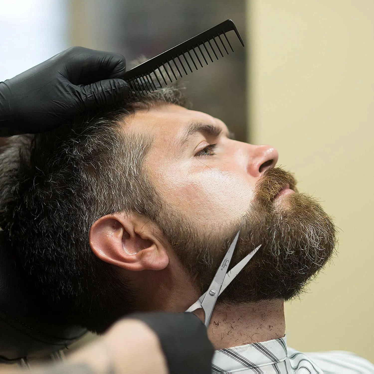 barber trimming beard with scissors